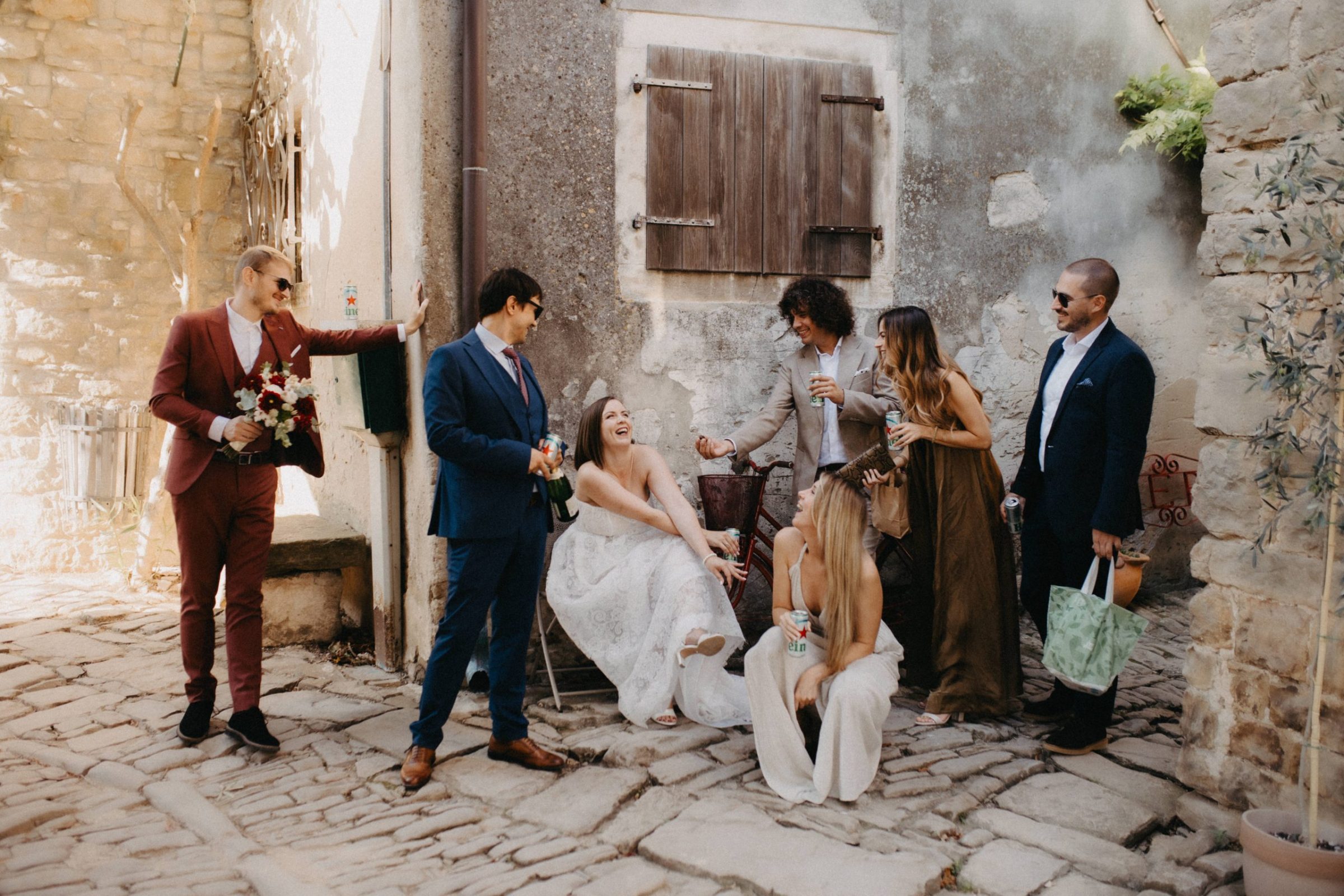 Mladenci i prijatelji smiju se i nazdravljaju u kamenim ulicama Grožnjana tijekom opuštenog vjenčanja bez formalnosti u Istri.